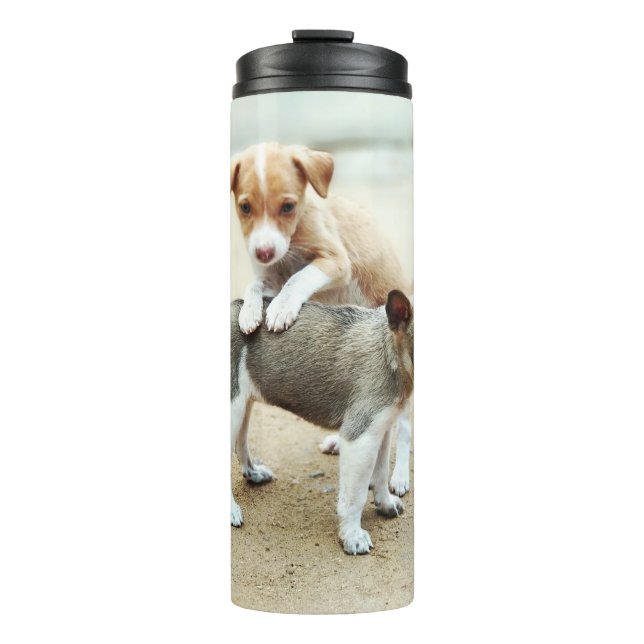 Niedliche Welpen spielen am Strand Thermosbecher (Vorderseite)