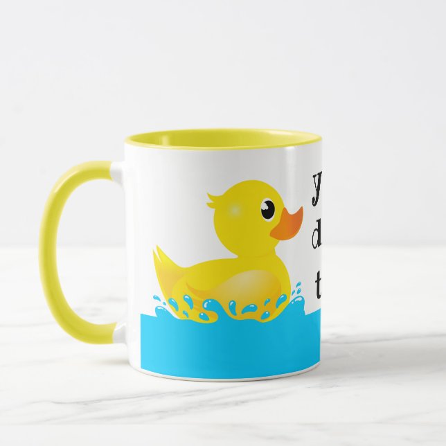 Niedlicher Gelber Gummi-Ente, der sich um Tasse (Links)