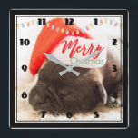 Niedlicher Mops in einer Roten Weihnachtsmannmütze Quadratische Wanduhr<br><div class="desc">Eine Uhr mit einem bezaubernden Foto eines Mops Welpen,  der beim Tragen einer roten Weihnachtsmannmütze schläft. Fröhliche Weihnachten ist auf der Hutband geschrieben,  in einem trendigen handgeschriebenen Schriftart,  in den festlichen Farben rot und grün. Weihnachtsbeleuchtung,  die über die Decke ragt,  schafft zusätzlichen saisonalen Flair.</div>