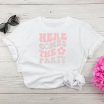 Niedlicher Retro-Script-Junggeselinnen-Abschied T-Shirt<br><div class="desc">Niedlicher Junggeselinnen-Abschied T - Shirt mit "Here Comes The Party" in einem lark-rosa und taupe Retro-Schriftart und einer Abbildung einer Blume im Stil der 70er Jahre. Für die Braut steht eine koordinierende Jacke "Here Comes The Bride" zur Verfügung.</div>