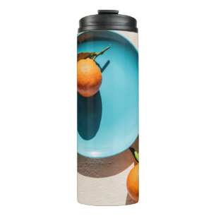 Orangenfrüchte auf Platte Thermosbecher
