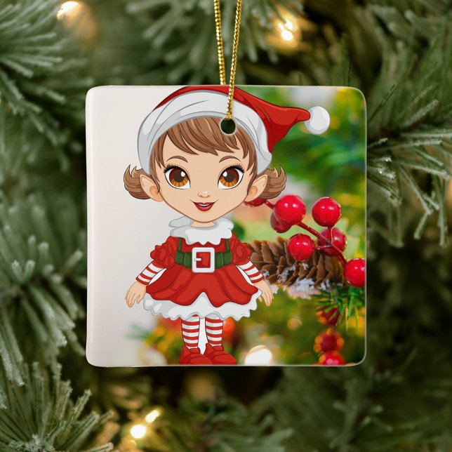 Ornement En Céramique Petite Fille de Santa Festive  (Elf is dressed in a festive red and white outfit, stands against a backdrop of a decorated tree.)