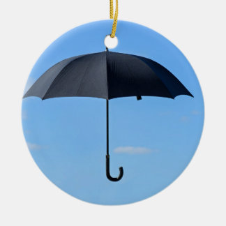 Ornement En Céramique Un parapluie noir vole dans le ciel bleu