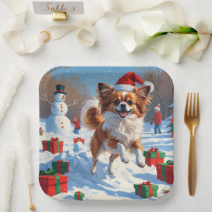 Papillon Hund läuft im Schnee mit Weihnachtshut Pappteller