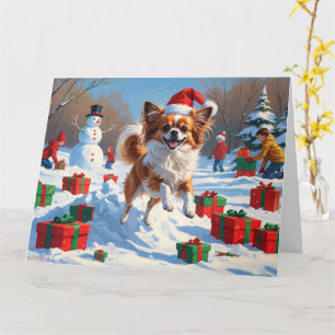 Papillon-Hund läuft im Schnee mit Weihnachtsmütze Karte