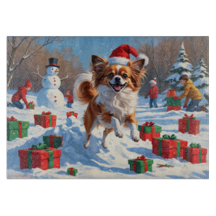 Papillon-Hund läuft im Schnee mit Weihnachtsmütze Schneidebrett