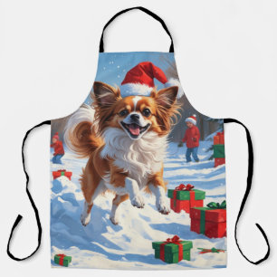 Papillon-Hund läuft im Schnee mit Weihnachtsmütze Schürze