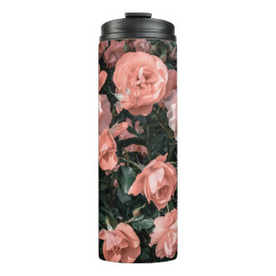 Pastellrosa Rosen, die im Garten in weichem Li wac Thermosbecher