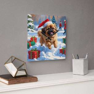 Pekingese-Hund läuft im Schnee mit Weihnachtsmütze Quadratische Wanduhr