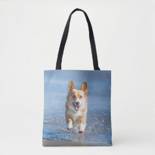 Pembroke-Walisercorgi-Hund, der auf den Strand Tasche