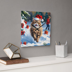 Persische Katze sitzt im Schnee mit Weihnachtshut Quadratische Wanduhr