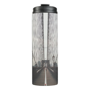 PERSON AUF BRÜCKE THERMOSBECHER