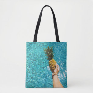 Person holding yellow pineapple tasche