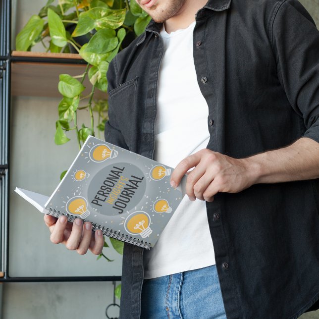 Personal Insights Journal Lightbulle Notebook Notizblock (A man looking at his notebook which is entitled Personal Insights Journal, covered in lightbulbs)