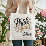 Personalized Gold Bride Squad Bachelorette Party Tragetasche<br><div class="desc">Get ready for the ultimate girls' getaway with this chic Bride Squad tote bag! Featuring elegant gold-toned typography and sparkling diamond accents, this bag is the perfect accessory for bachelorette weekends, bridal showers, or as a stylish wedding welcome bag. Durable and spacious, it's designed to hold all your party essentials...</div>