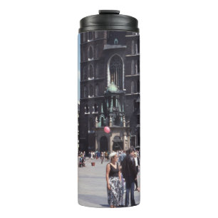 PERSONEN, DIE NEBEN EINER BETONKATHEDRALE STEHEN THERMOSBECHER