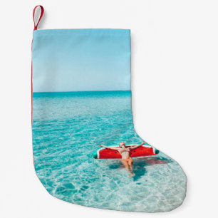 Petite Chaussette De Noël Femme sur lilo dans l'eau de mer. Fille se relaxer