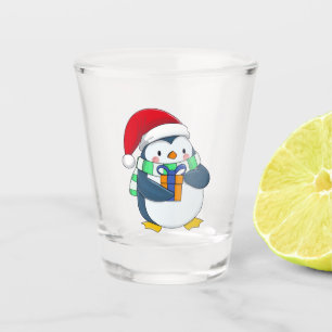 Pinguin in einem Weihnachtshut mit Geschenk Schnapsglas