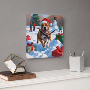 Pitbull Hund läuft im Schnee mit Weihnachtshut Quadratische Wanduhr
