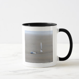 Plastikgabel, die dazu im sandigen Strand haftet Tasse