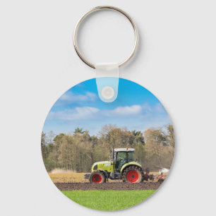 Porte-clés Farmer on tractor plowing sandy soil in spring