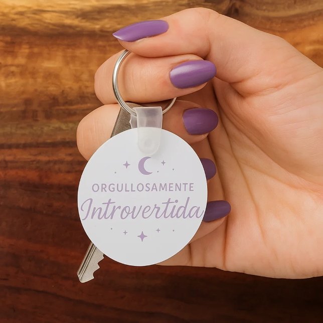 Porte-clés Llavero redondo “Orgullosamente introvertida”  (Una mano de mujer con sus uñas pintadas de morado cogiendo unas llaves con su llavero favorito.)