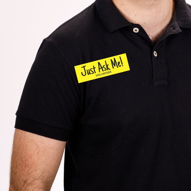 Porte-nom Volontaire Jaune Me Demandez Simple (Man wearing black shirt with yellow "just ask me" volunteer name tag badge.)
