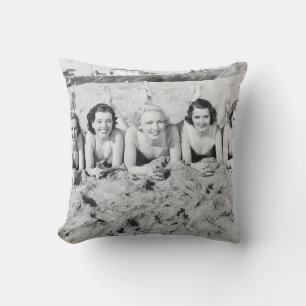 Portrait von fünf jungen Frauen, die am Strand lie Kissen