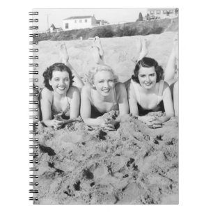 Portrait von fünf jungen Frauen, die am Strand lie Notizblock