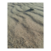 Le vent forme des vagues de sable, autour de galet
