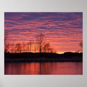 Poster Un coucher de soleil brillant se reflète dans la r