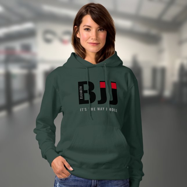 Pull À Capuche Personnalisé BJJ féminin (Dark green woman's BJJ hoodie worn by a female model in a gym.)