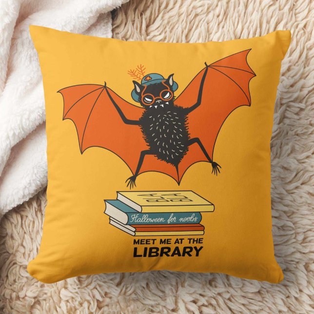 Reading Bat | Whimsical Librarian with Books Kissen (yellow pillow with a cute cartoon bat with eyeglasses and hat flying over some books)