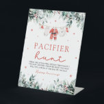 Red Christmas Santa Baby Schnuller Hunt Kinderdusc Sockelschild<br><div class="desc">Das Red Christmas Santa Baby Schnuller Hunt Baby Shower Game Sign verleiht Ihrer Babydusche eine Touch von Urlaubsspass und Spannung. Dieses Schild mit weißem Hintergrund mit festlichen roten Schneeflocken, fröhlichen roten Beeren, winterlicher Eukalyptusgrün und Babykleidung im Weihnachtsstil lädt die Gäste zum Schnuller Hunt ein. Die Gäste können in der Umgebung...</div>