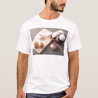 Rohe Champignonpilze und -zwiebeln auf der Tabelle T-Shirt