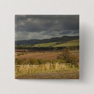 Rolling Hills und Berge unter einem bewölkten Button