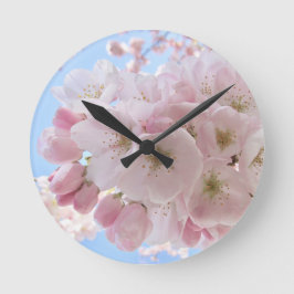 Rosa Blüten blauer Himmel. Runde Wanduhr