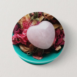 Rosen-Quarz-Herz in einem Bett der Button