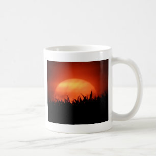 Roter Sonnenuntergang hinter schwarzem Gras Kaffeetasse
