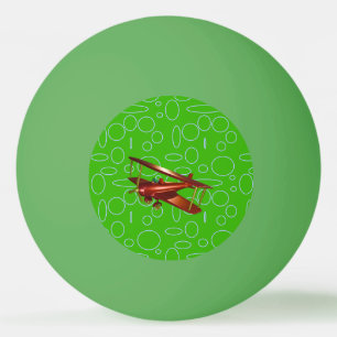 Rotes Doppeldeckerflugzeug auf grünen Kreisen und Tischtennisball
