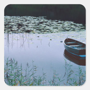 Ruderboot auf einem kleinen See, umgeben von Wasse Quadratischer Aufkleber