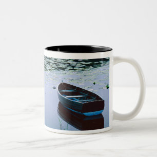 Ruderboot auf einem kleinen See umgeben von Wasser Zweifarbige Tasse