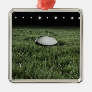 Rugbyball, der auf der Grasneigung sitzt Silbernes Ornament