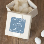 Rustic Dusty Blue Floral Wildblume Gastgeschenk Ho Quadratischer Aufkleber<br><div class="desc">Dieser hübsche,  rustikale Aufkleber mit Gastgeschenk Hochzeit ist mit einem schönen,  staubblauen Hintergrund,  weißen Wildblumen und eleganter Typografie ausgestattet. Es ist das perfekte Design für eine rustikale,  elegante Hochzeit und koordiniert mit unserer rustikalen Wildblume-Kollektion...  Weitere Informationen finden Sie in der Designsammlung.</div>