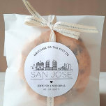 San Jose Skyline | Begrüßung Runder Aufkleber<br><div class="desc">Erweitern Sie Ihre Hochzeitspakete oder Event-Gastgeschenke mit einem individuellen Set von Begrüßungsaufklebern! Diese eleganten, aber minimalistischen Aufkleber sind auf eine Hochzeit in der schönen Stadt San Jose, Kalifornien, zugeschnitten. Sie verfügen über eine moderne Skyline aus Deko, die den Namen der Stadt trägt und darunter integriert ist. Alle Elemente des Designs,...</div>