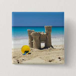 Sand-Schloss und Eimer auf tropischem Strand Button