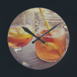 Sangria and Sunshine Runde Wanduhr<br><div class="desc">This image shows a refreshing glass and pitcher of citrus sangria, perfect for a warm day. The fresh slices of lemon and orange add bright colour and hint of natural sweetness. One glass sits ready to enjoy while sangria is being poured from a small glass pitcher beside it, perfect for...</div>