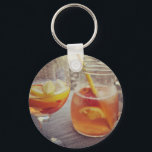 Sangria and Sunshine Schlüsselanhänger<br><div class="desc">This image shows a refreshing glass and pitcher of citrus sangria, perfect for a warm day. The fresh slices of lemon and orange add bright colour and hint of natural sweetness. One glass sits ready to enjoy while sangria is being poured from a small glass pitcher beside it, perfect for...</div>