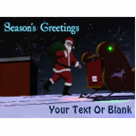 Santa on the Roof - Die Grüße der Saison Fotoskulptur Magnet<br><div class="desc">Der Weihnachtsmann wird auf dem Dach eines Hauses nach der Lieferung von Geschenken gesehen. Die roten und grünen Navigationsleuchten seines Schlittens spiegeln sich auf dem Schnee auf der Dachterrasse wider, und das persönliche North Pole Nummernschild des Weihnachtsmanns ist sichtbar.Text mit dem Text "Die Grüße der Jahreszeit" erscheint ebenfalls zusammen mit...</div>