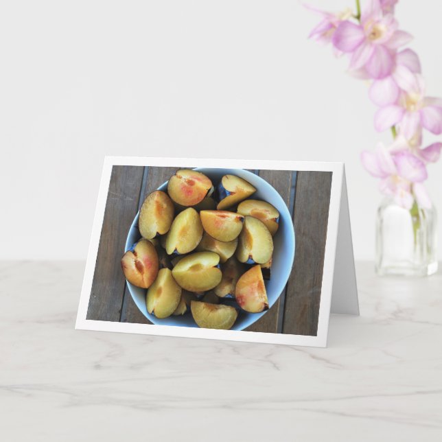 Schale aus geschnittenem Pflaumenfrucht auf Holzti Karte (Orchidee)